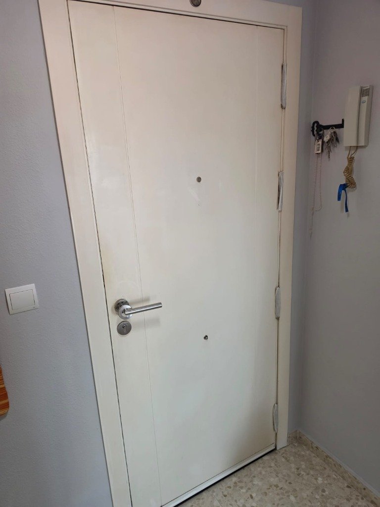Puerta blindada de entrada en tono madera oscura antes de lacar en Granada